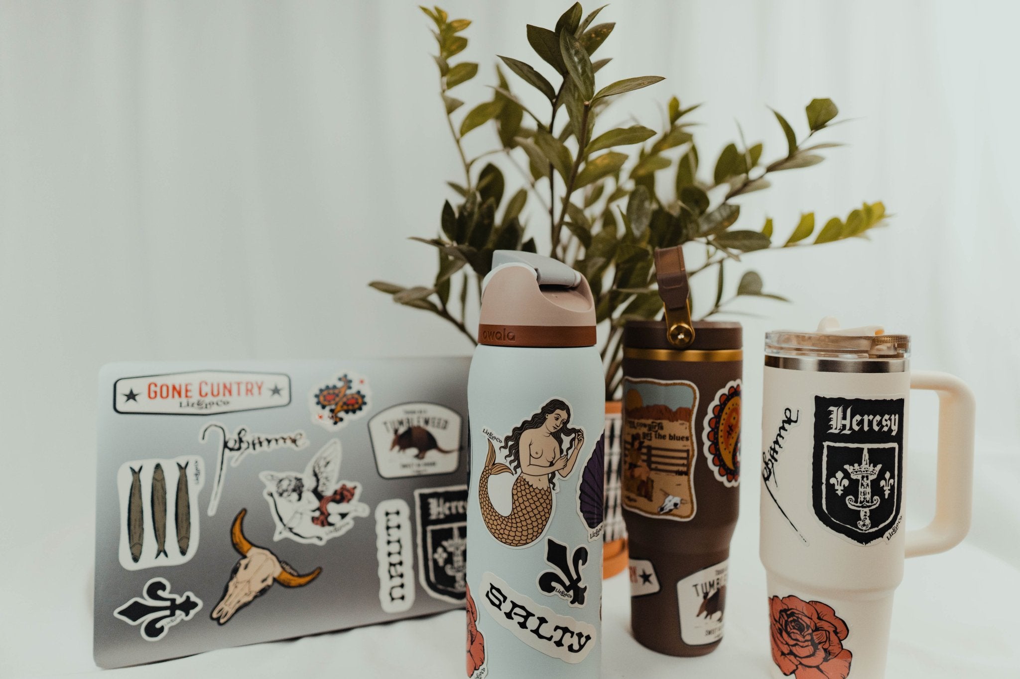 Collection of travel mugs with decorative stickers on a white background