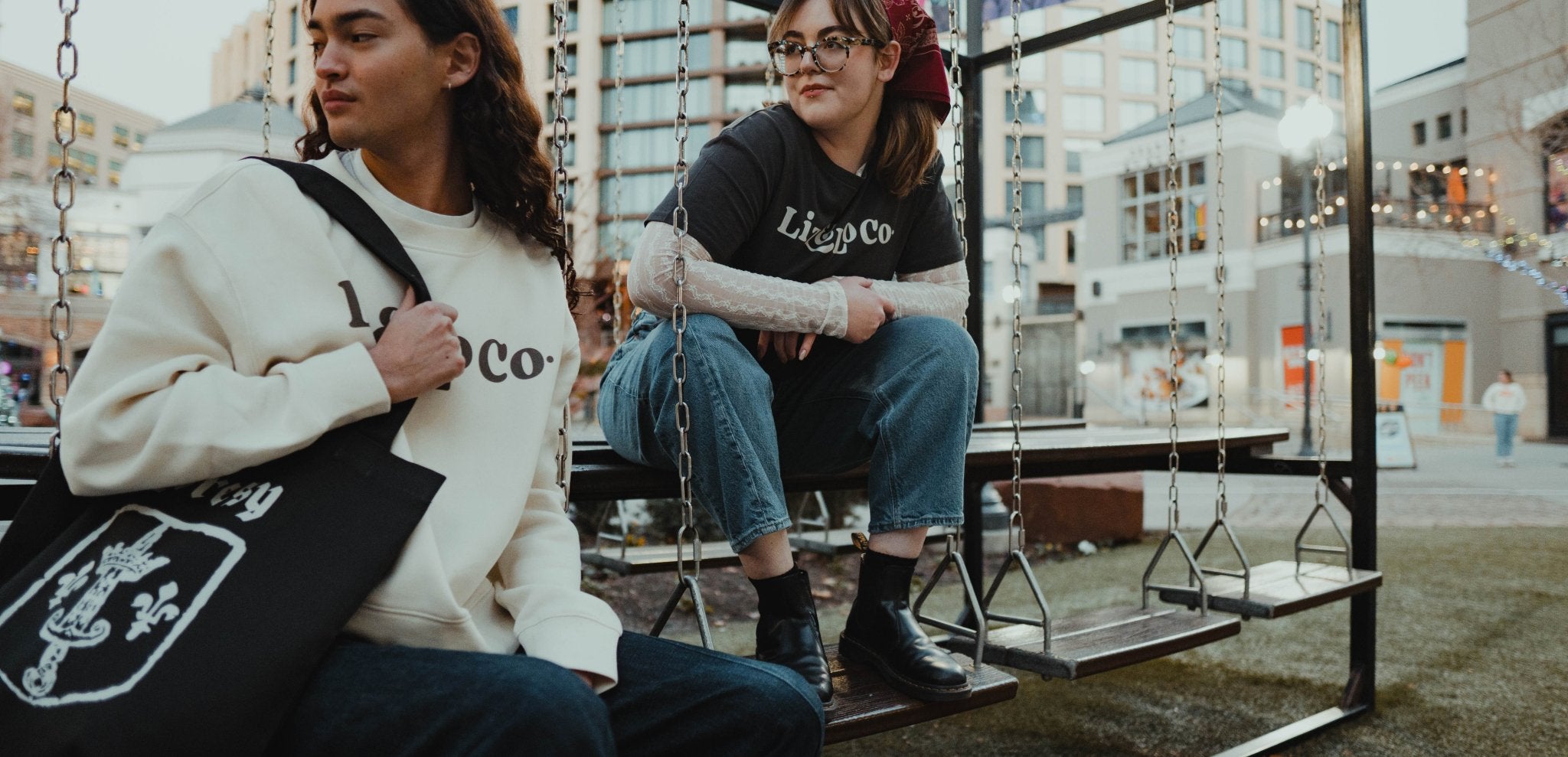 Two people sitting on a swing set in an urban setting
